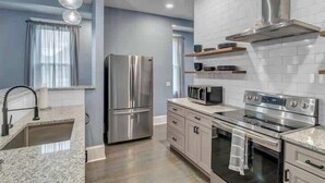 A modern kitchen with stainless steel appliances, a granite countertop, and a white backsplash. - Gigantic duplex in Springfield (Jacksonville)