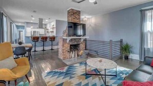 A modern living room with a fireplace, a ceiling fan, and a dining area with bar stools. - Gigantic duplex in Springfield (Jacksonville)