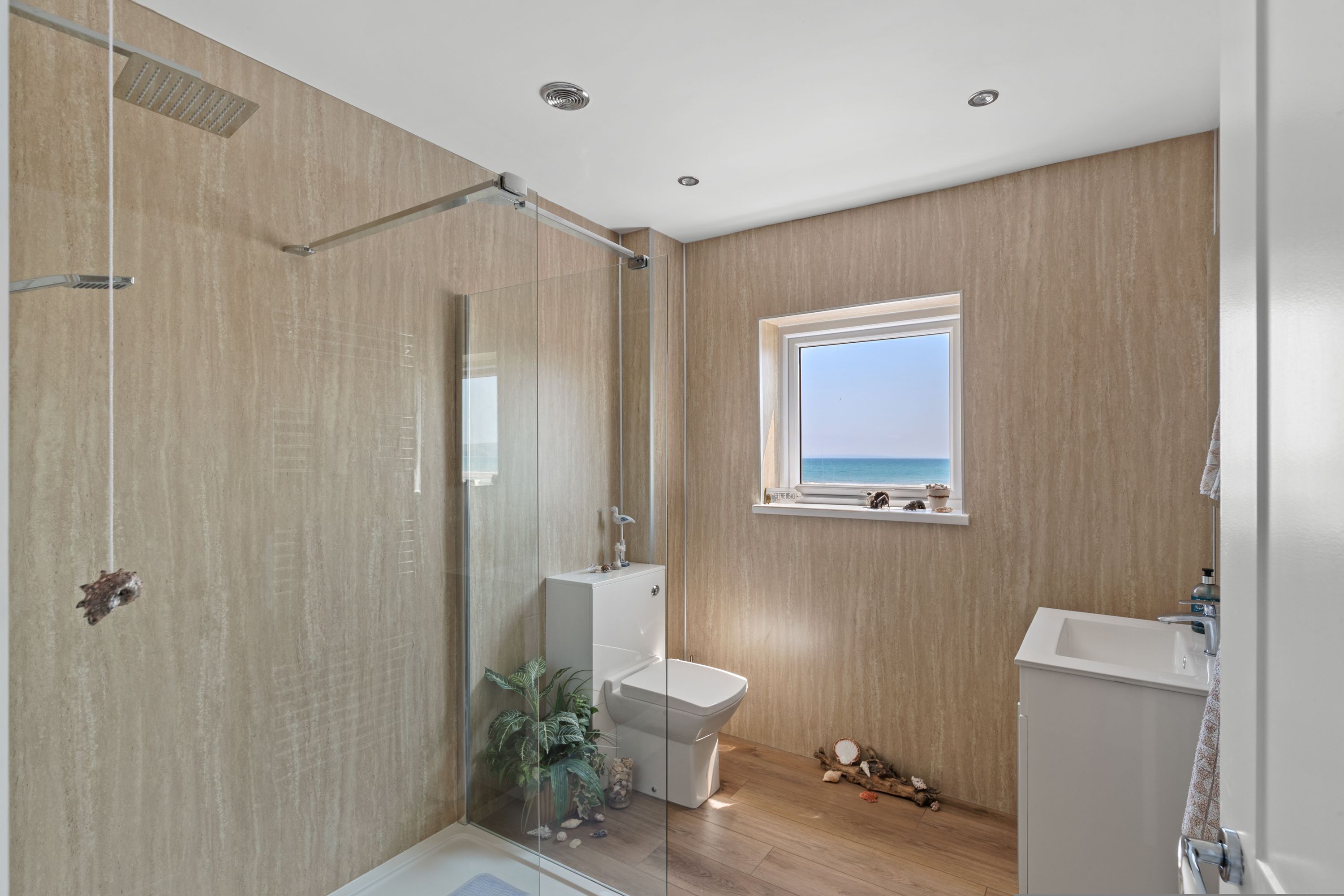 A modern bathroom with a glass shower enclosure, a toilet, and a sink.