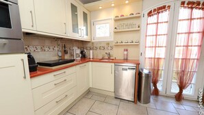 A kitchen with white cabinets, a stainless steel dishwasher, and a red countertop.