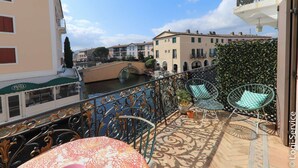 A balcony with outdoor furniture, a view of a canal, and buildings in the background.