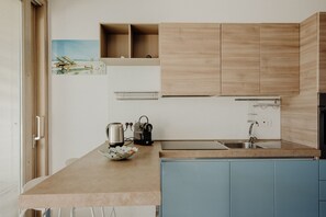 A kitchen with light wood cabinets, a blue countertop, and a stainless steel sink. - Residenza Lamandia in Capitolo (Monopoli)