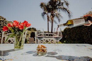 A table with two wine glasses, a bottle of wine, a vase with red flowers, and a bowl of snacks. - Residenza Lamandia in Capitolo (Monopoli)
