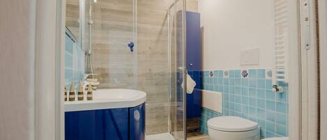 A bathroom with a glass shower enclosure, a white toilet, and a blue-tiled wall.