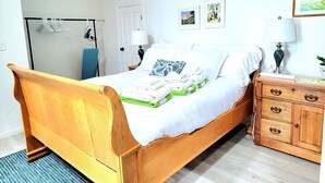 A bedroom with a wooden bed, a bedside table with a lamp, a dresser, and a radiator.