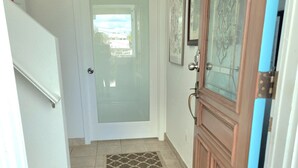 A hallway with a patterned doormat, a white door, and a blue-framed door.