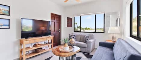 Una sala de estar moderna con televisor, sofá y mesa de centro.