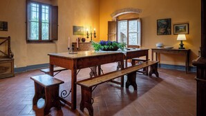 Una stanza con un tavolo di legno, panche, un'esposizione di fiori e una lampada.