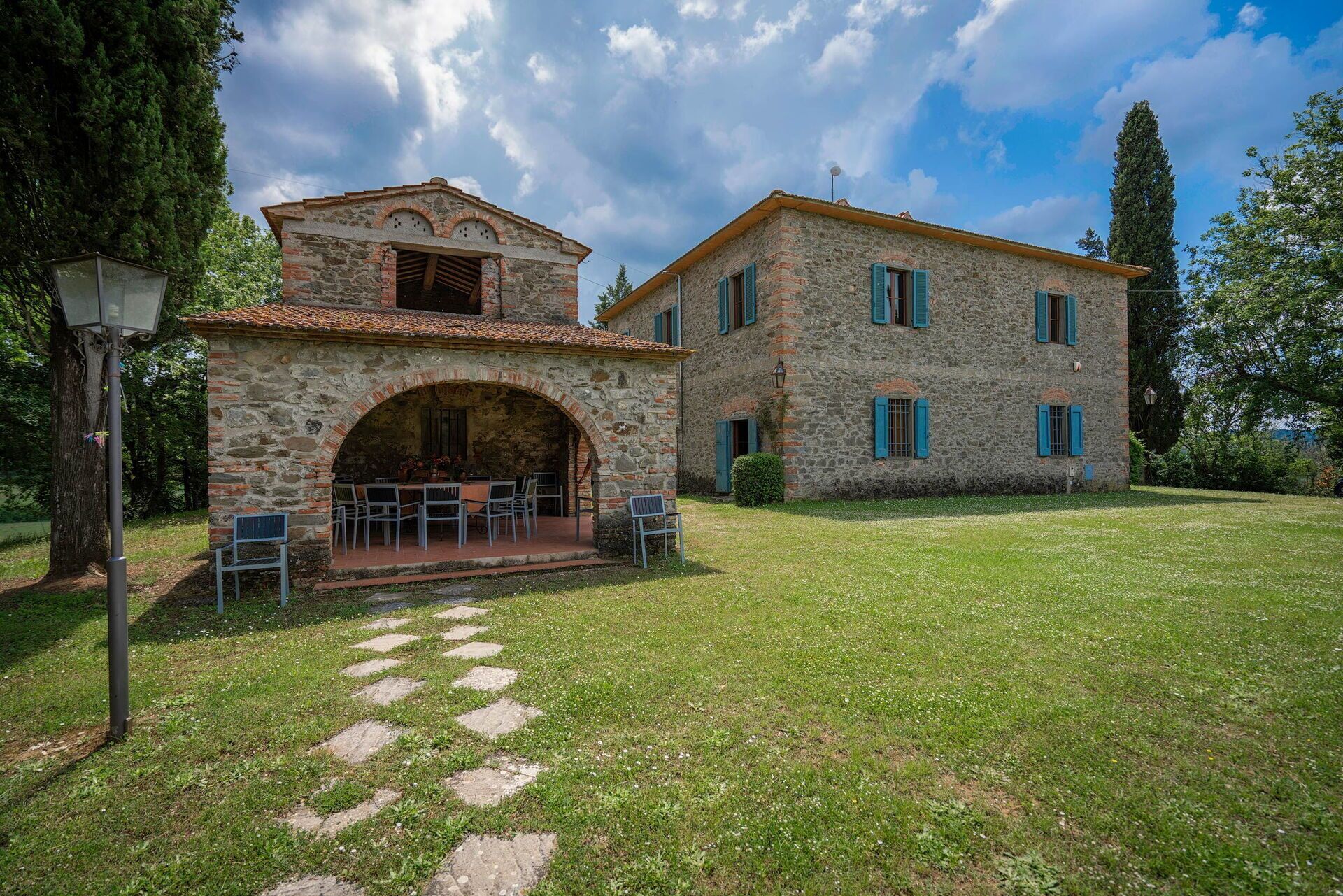 Un edificio in pietra con un arco centrale e un patio con posti a sedere all'aperto.