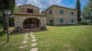 Un edificio in pietra con un arco centrale e un patio con posti a sedere all'aperto.