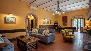 A cozy living room with a fireplace, a pool table, and a billiards table.