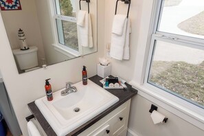 A bathroom with a white sink, two bottles of liquid soap, a tissue box, and a makeup set on the counter. - Water's Edge Retreat (Waverly)