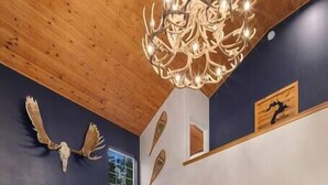A modern living room with a staircase, a fireplace, a sofa, and a chandelier. - Sandpoint Mountain Retreat (Bonner County)