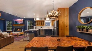 A modern kitchen with wooden cabinets, a central island, and a dining area with a herringbone-patterned table. - Sandpoint Mountain Retreat (Bonner County)