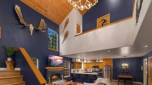 A spacious living area with a fireplace, a dining table, and a kitchen in the background. - Sandpoint Mountain Retreat (Bonner County)