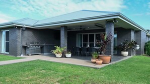 A modern house with a covered patio, outdoor grill, and potted plants. - Luxe on Lincoln - Close to Zoo, Rejuvenating Pool (Dubbo)
