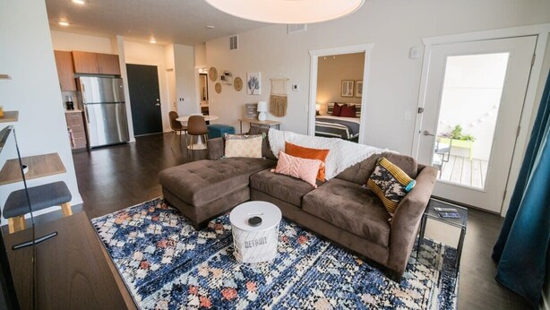 Ein modernes Wohnzimmer mit einem Ecksofa, einem runden Couchtisch und einem Teppich mit Muster.
