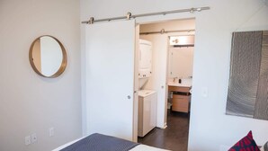 Ein Hotelzimmer mit Bett, rundem Spiegel, Kleiderschrank und angrenzendem Badezimmer.
