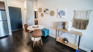 Eine moderne Küche mit Essbereich, ausgestattet mit einem runden Tisch, zwei Stühlen, einem blauen Hocker und einem Willkommensschild.