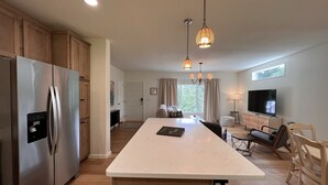 Een moderne keuken met een groot eiland, roestvrijstalen apparatuur en een eethoek met televisie en zitplaatsen.