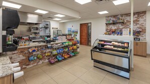 A commercial kitchen with a brick counter, a refrigerated display case, and a microwave. - 9th Hole Clubhouse Stroll (St. George)