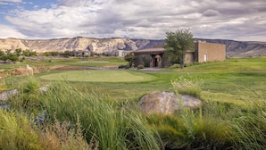 A golf course with a clubhouse, a pond, and mountains in the background. - 9th Hole Clubhouse Stroll (St. George)
