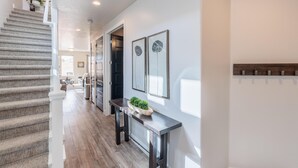 A staircase leading to a living area with a dark wood floor, a console table with a plant, and framed artwork on the wall. - Desert Skies (St. George)