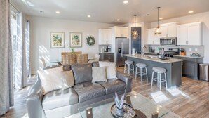 A modern kitchen with white cabinets, stainless steel appliances, and a central island with stools. - Desert Skies (St. George)