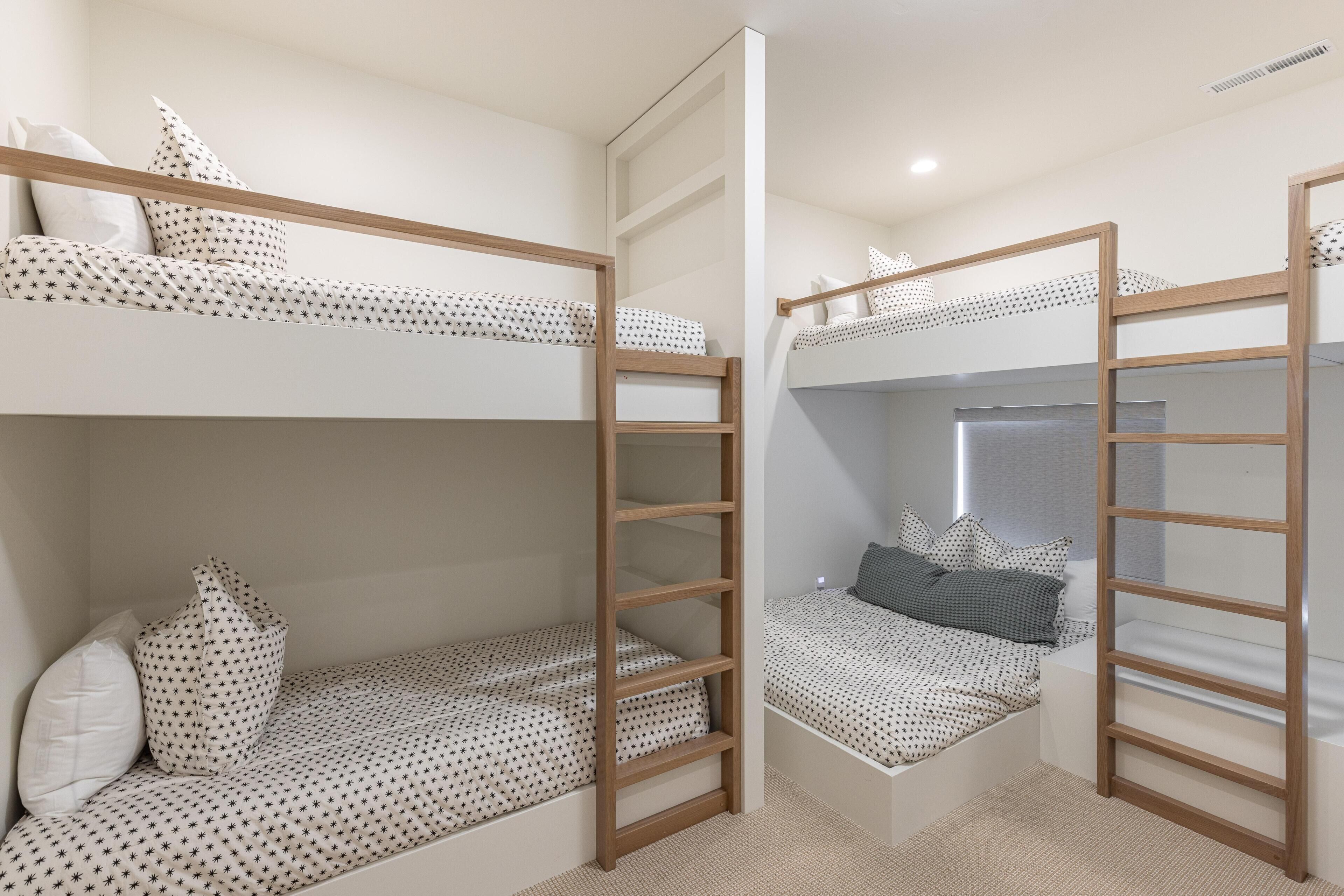 Une chambre avec un lit superposé, une petite échelle, un petit bureau et une fenêtre.