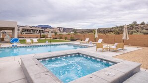 Una piscina con lettini, una vasca idromassaggio e vista sulle montagne.