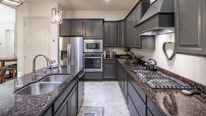 A modern kitchen with granite countertops, stainless steel appliances, and dark cabinetry. - 1 Top Ledge (St. George)
