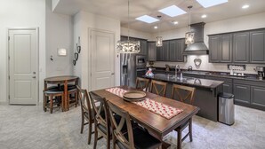 A modern kitchen with a central island, pendant lighting, and a view of the living area. - 1 Top Ledge (St. George)