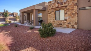 A modern building with a stone facade, a covered patio with seating, and a well-maintained gravel area. - 1 Top Ledge (St. George)