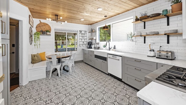 Een moderne keuken met witte kasten, een zwart-wit vloer en houten balken in het plafond.