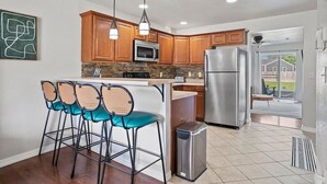Una cocina moderna con armarios de madera, electrodomésticos de acero inoxidable y una barra con taburetes.
