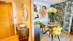 A dining area with a round table, yellow chairs, and a woven light fixture. - The Cliffs - Piccola Home (Ortigueira)