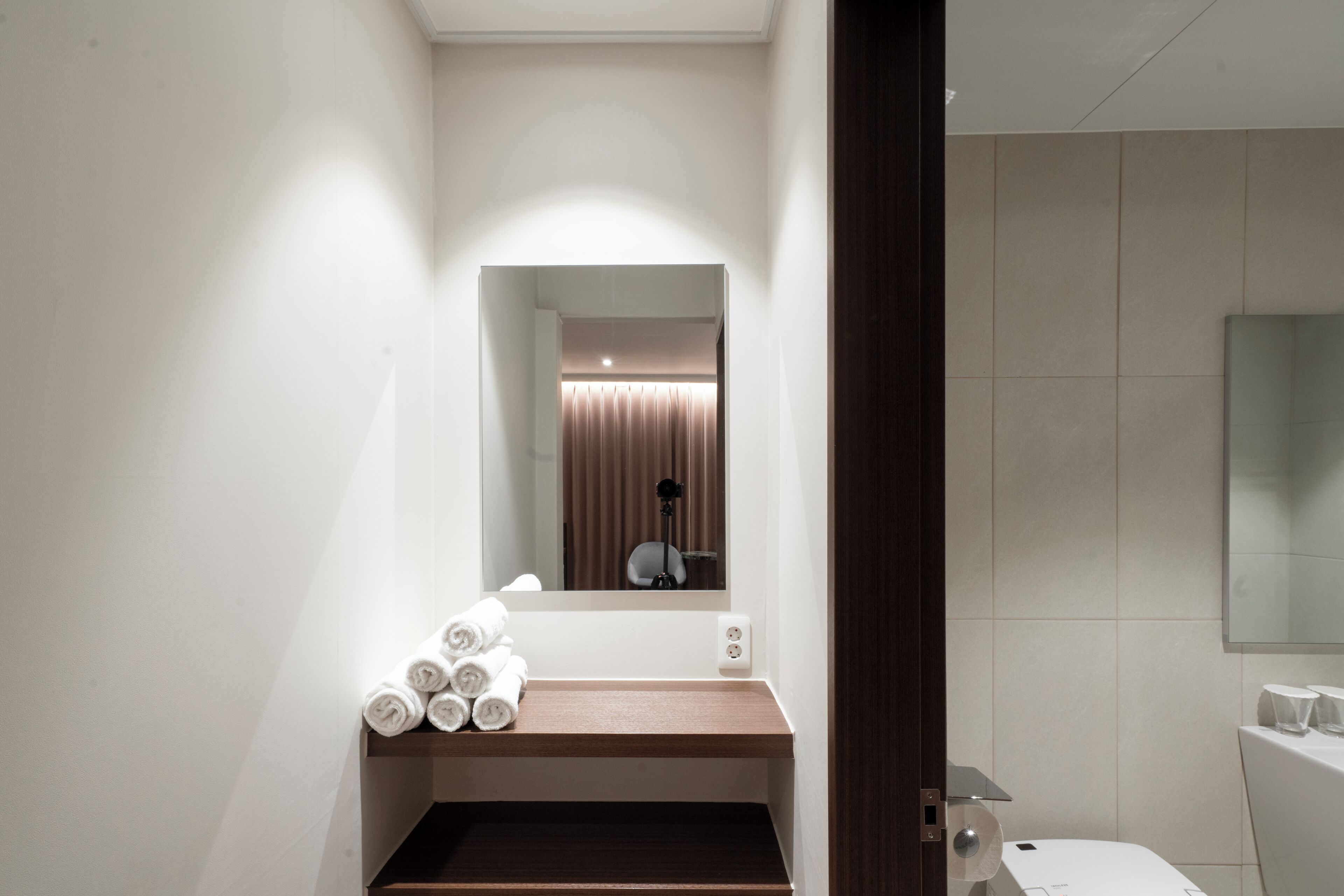 A bathroom with a mirror, a sink, a towel rack, and a toilet.