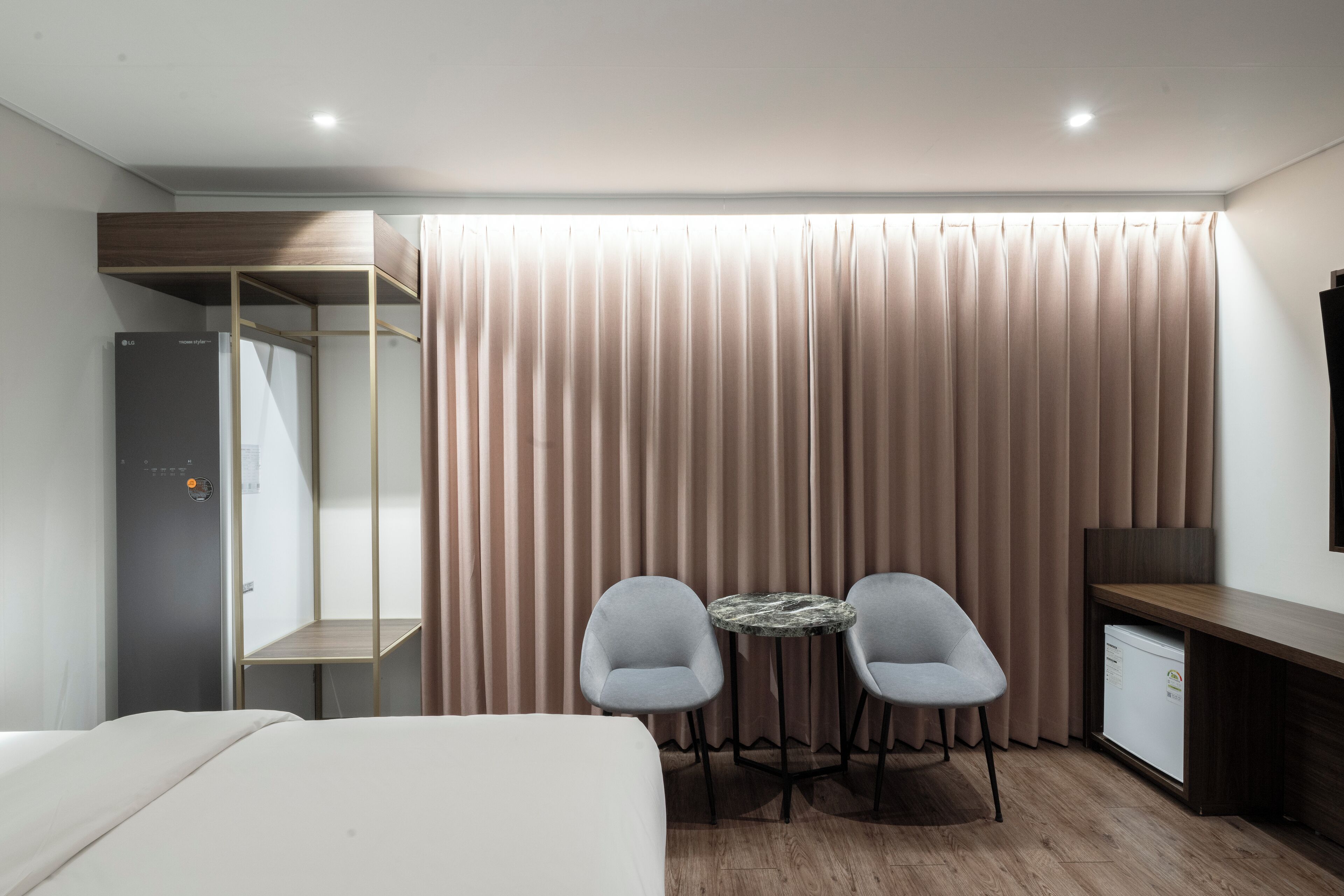 Habitación de hotel con cama, escritorio, dos sillas, una mesita, armario y cortina.