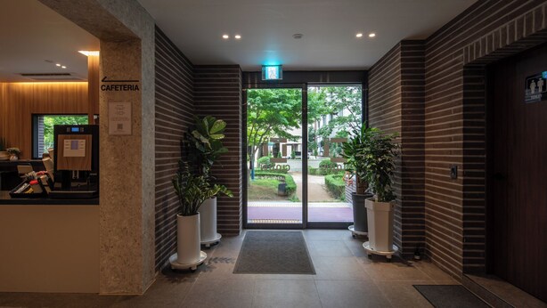 Un vestíbulo de hotel con una recepción, una máquina de café y plantas en macetas.