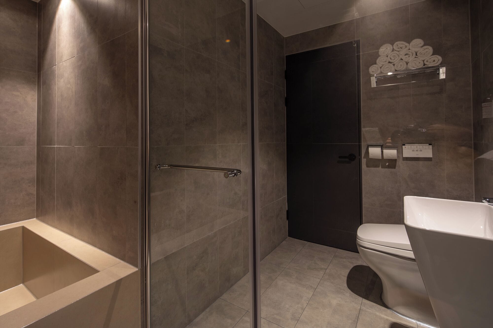 A modern bathroom with a glass shower enclosure, a toilet, and a built-in bathtub.