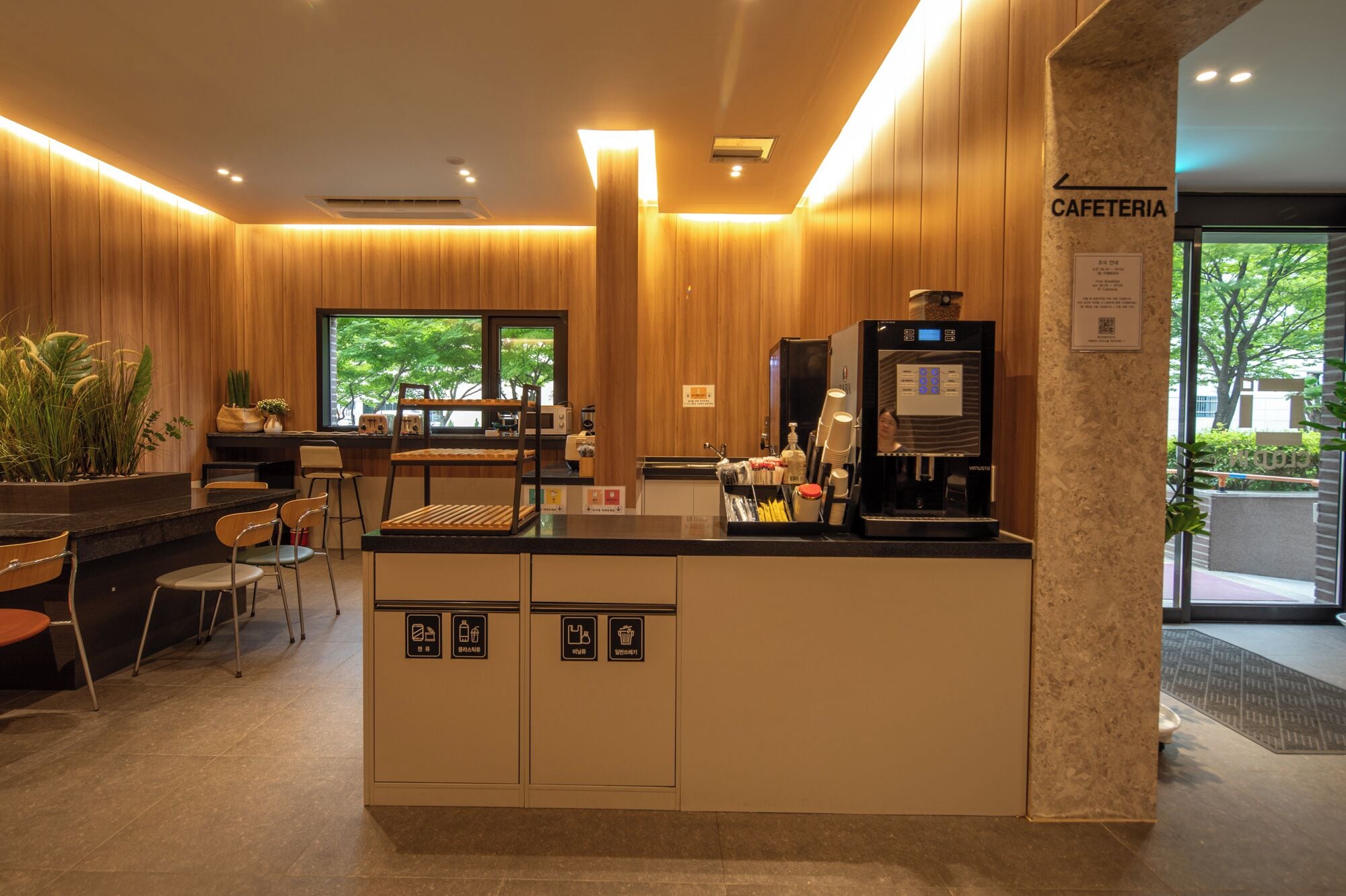 Ein modernes Café-Interieur mit Holzvertäfelung, einer Kaffeemaschine und einer Sitzgruppe mit Stühlen und einem Tisch.