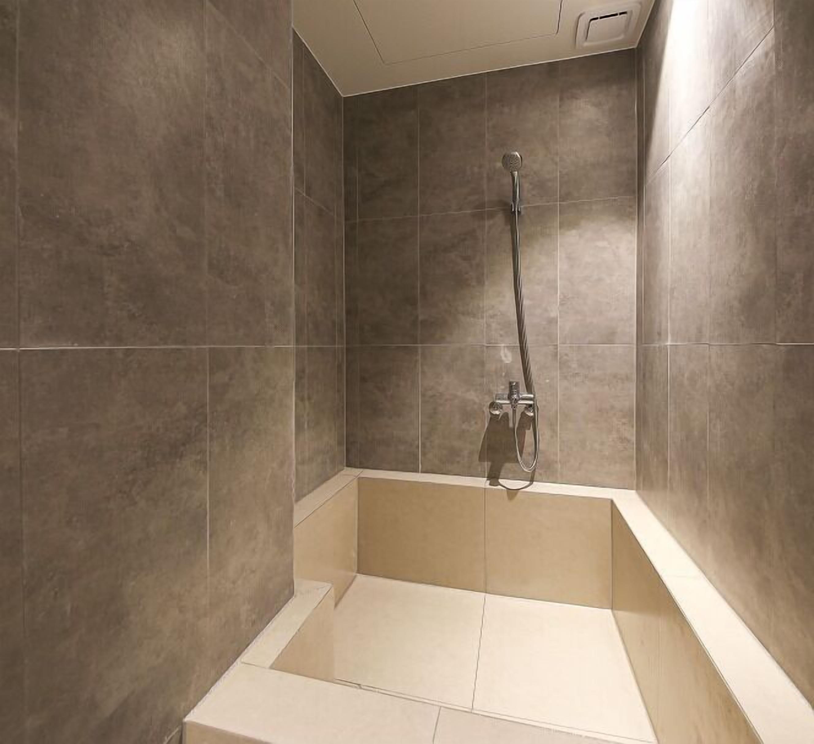 A modern shower with a handheld showerhead and a wall-mounted faucet.