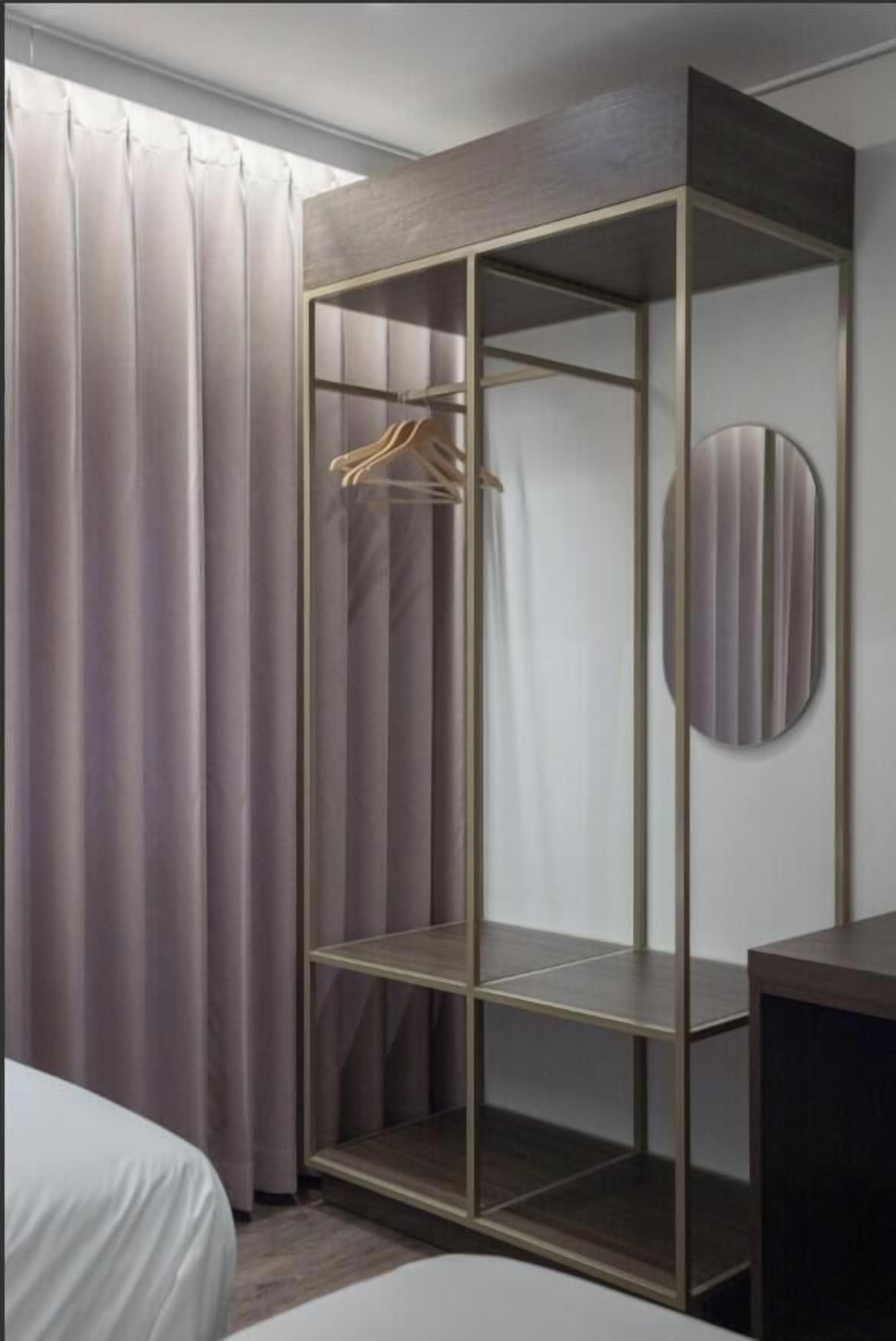 A room with a wardrobe, a bed, and a round mirror.
