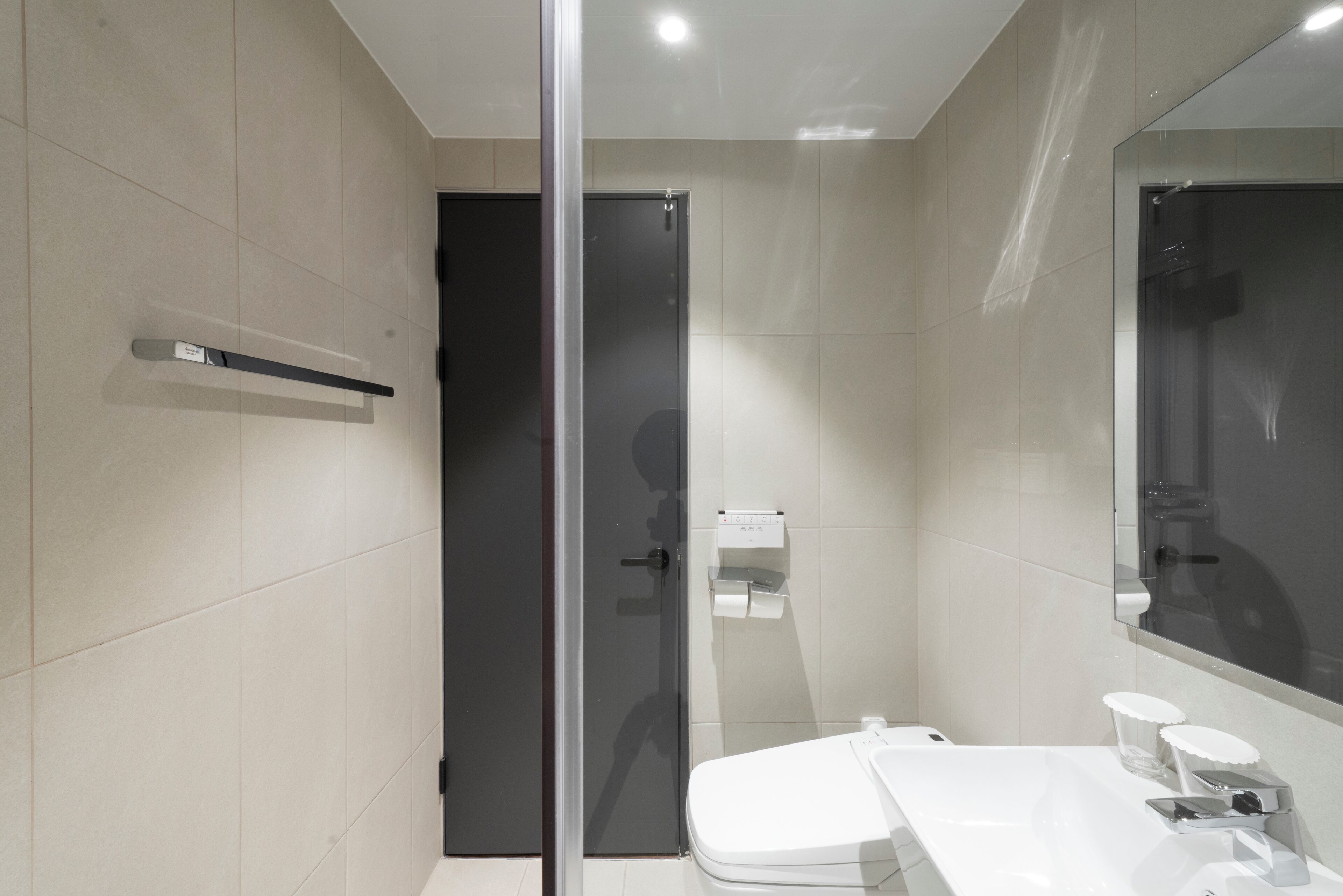 Un baño moderno con cabina de ducha de vidrio, un lavabo blanco y un espejo grande.