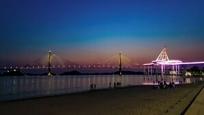 Una playa con un puente al fondo.