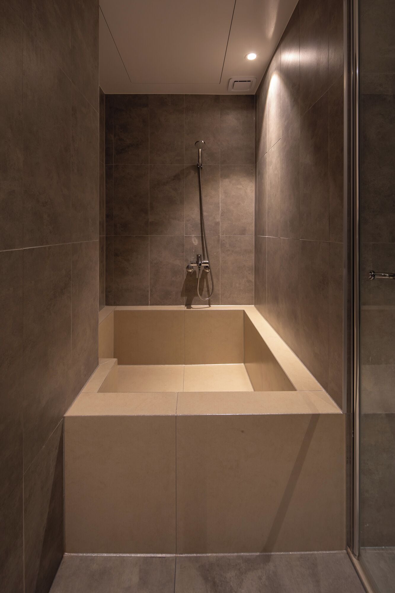 A modern bathroom with a large bathtub, a showerhead, and a glass door.
