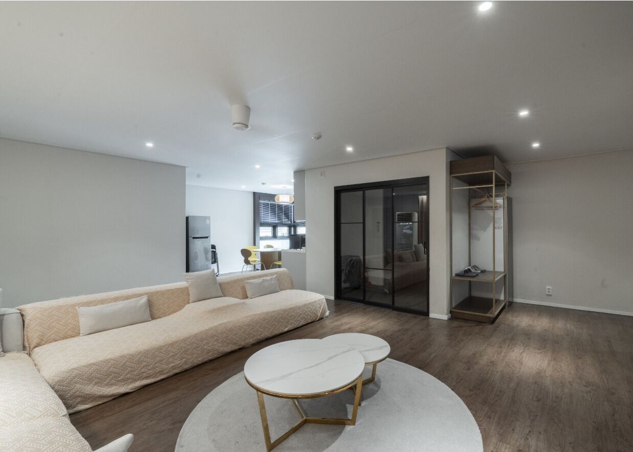 A modern living room with a sofa, a coffee table, and a sliding glass door leading to a balcony.