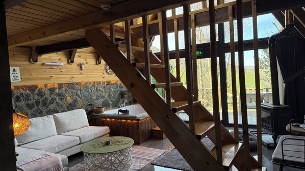 Interior em madeira com sofá, mesa, lareira e escada.
