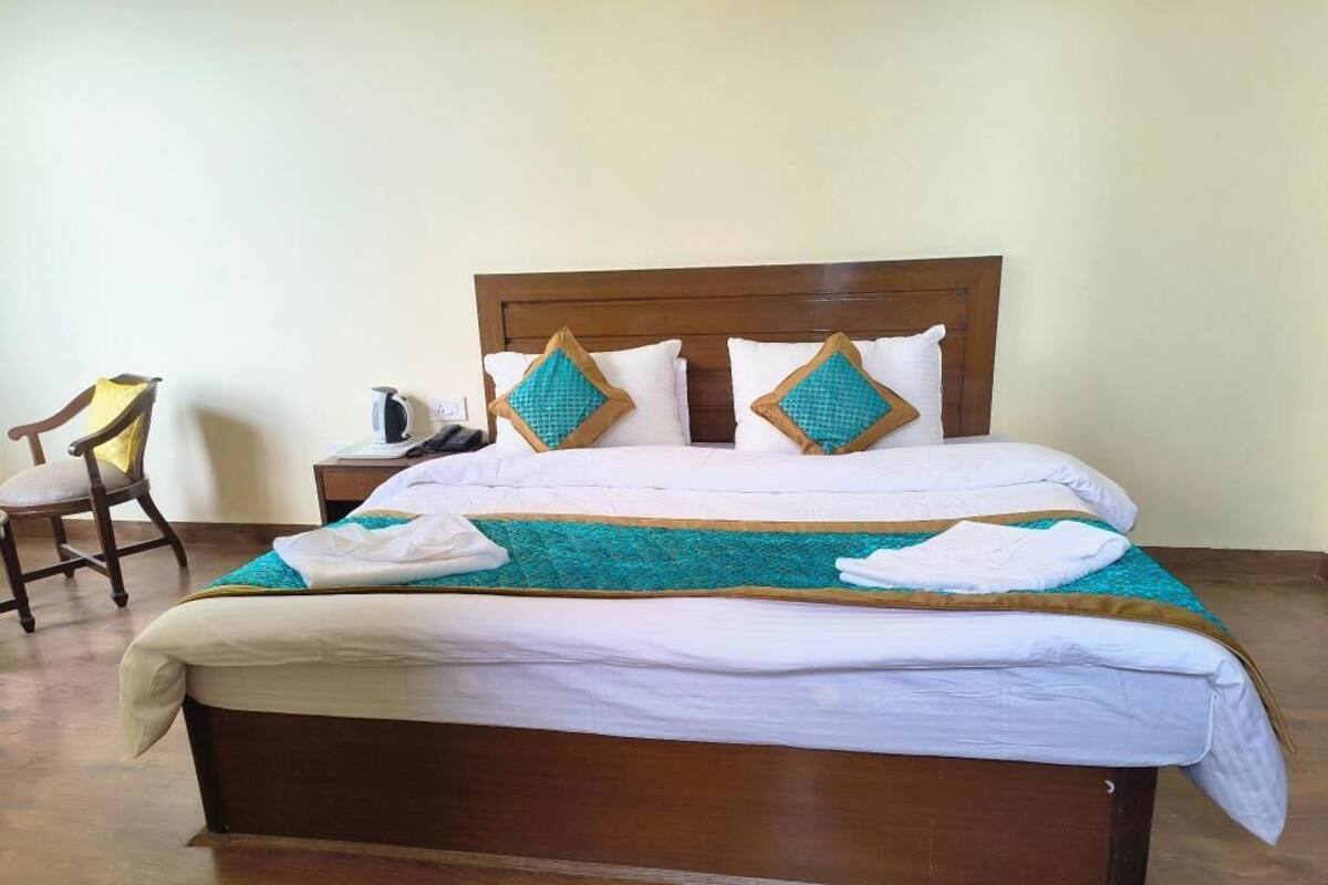 A neatly made bed with a wooden headboard, white bedding, and teal and brown decorative pillows.