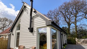 Una casa con un amplio ventanal, una chimenea y un patio con sillas.